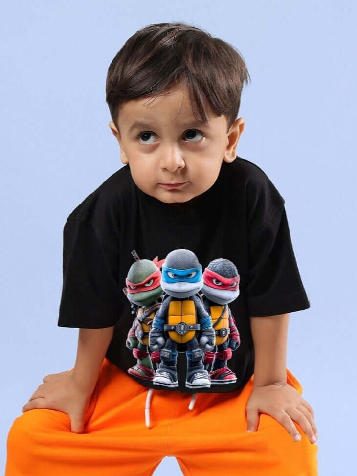 Young boy wearing Ninja Turtles T-Shirt for Boys and Girls Black, featuring cartoon turtles on front, showcasing playful kids' fashion.