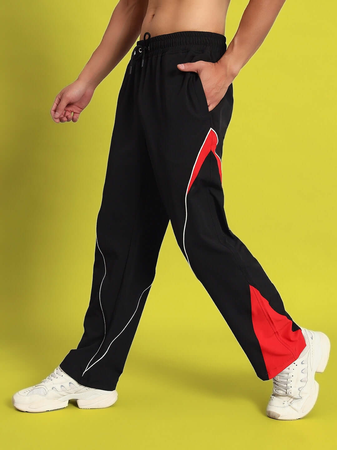 Person wearing NISSAN parachute cargo pants in black-red, showcasing stylish design and custom fit option against a yellow background.