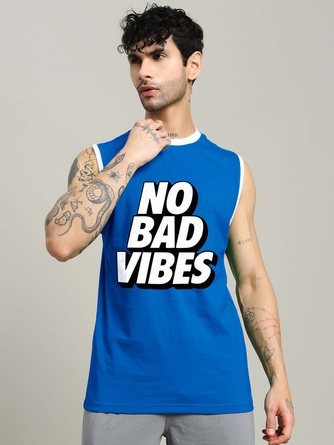 Man wearing NO BAD VIBES SLEEVLESS GYM T-SHIRT BLUE for workouts emphasizing positivity and style.