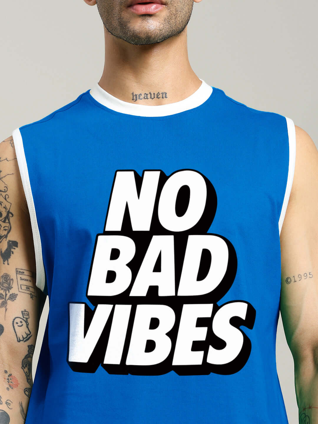 Man wearing NO BAD VIBES SLEEVLESS GYM T-SHIRT BLUE with bold graphic print, ideal for athletes promoting positivity during workouts.