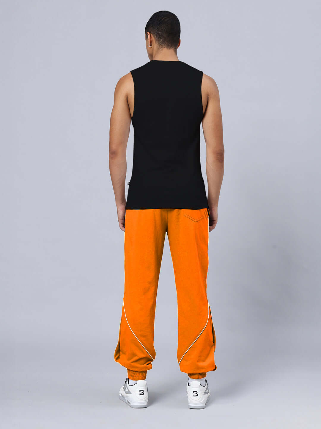 Rear view of person wearing NO GRIT NO GLORY GYM RELAXED FIT CO-ORD SET BLACK-ORANGE with black top and orange pants.