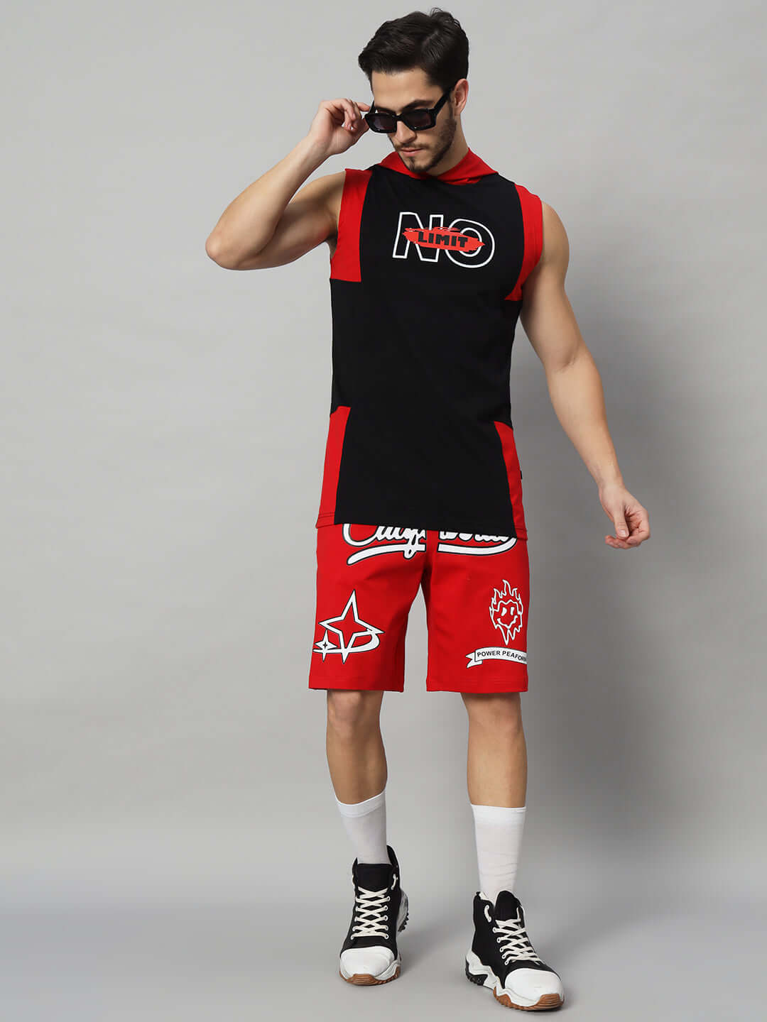 Model wearing No Limit Gym regular red-black t-shirt, customizable fit, handmade quality, with matching shorts, sunglasses, and sneakers.