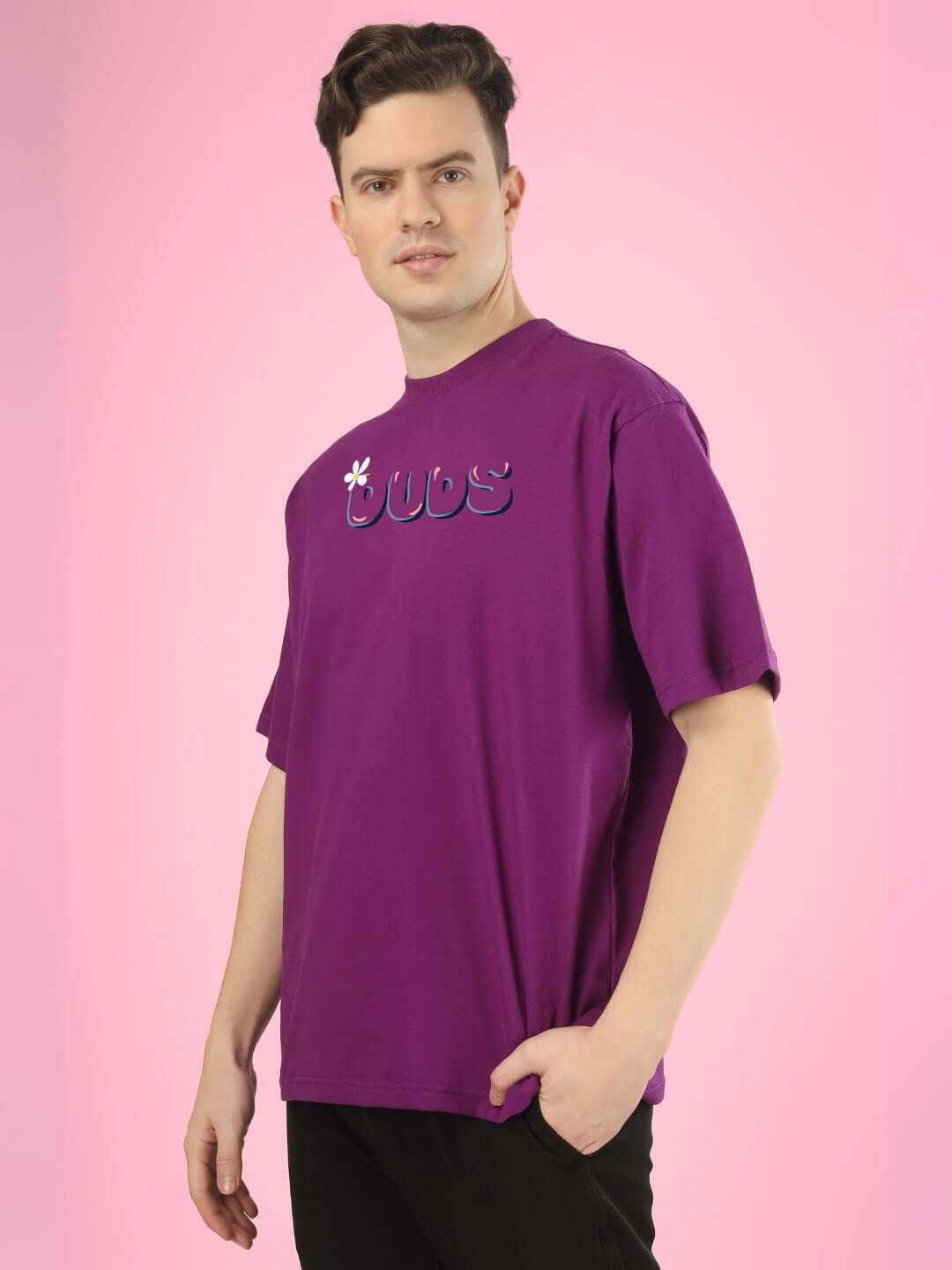 Man wearing NO POS WOW OVER-SIZED PRINTED T-SHIRT PURPLE, showcasing bold streetwear style on a pink background.