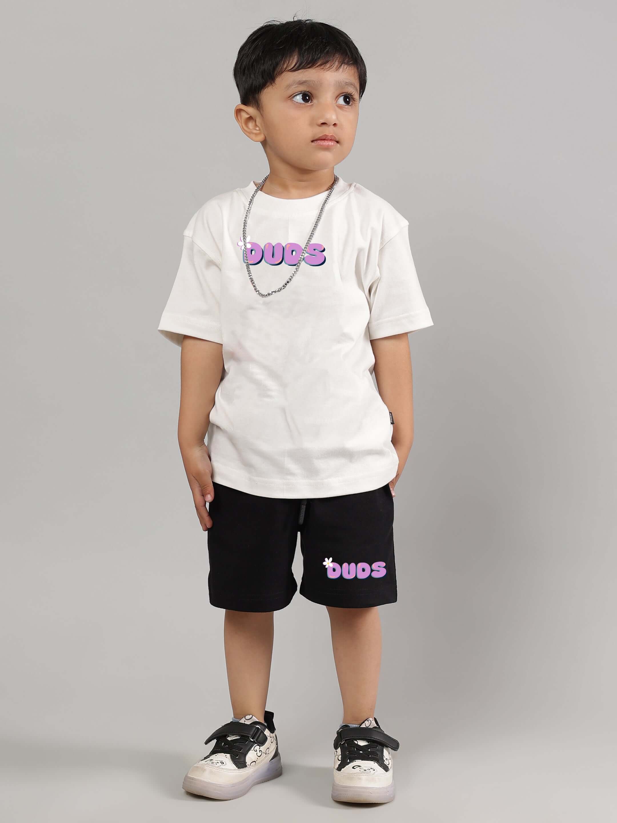 Young boy wearing an off-white NO POS WOW T-shirt by DUDS, perfect for both boys and girls, showcasing a trendy casual look.