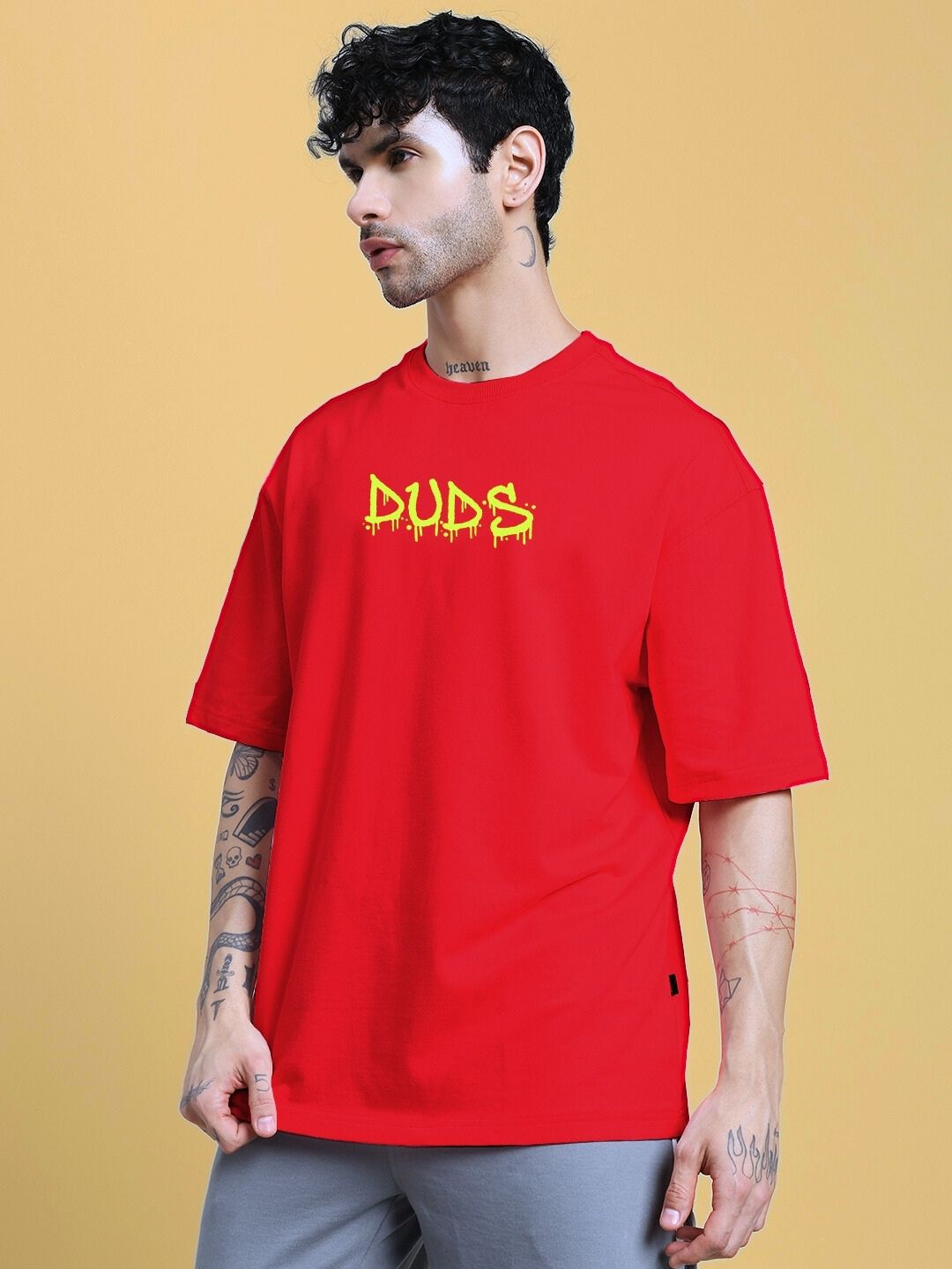 Model wearing NO WAR OVER-SIZED T-SHIRT IN RED with graphic print, standing against a yellow background.