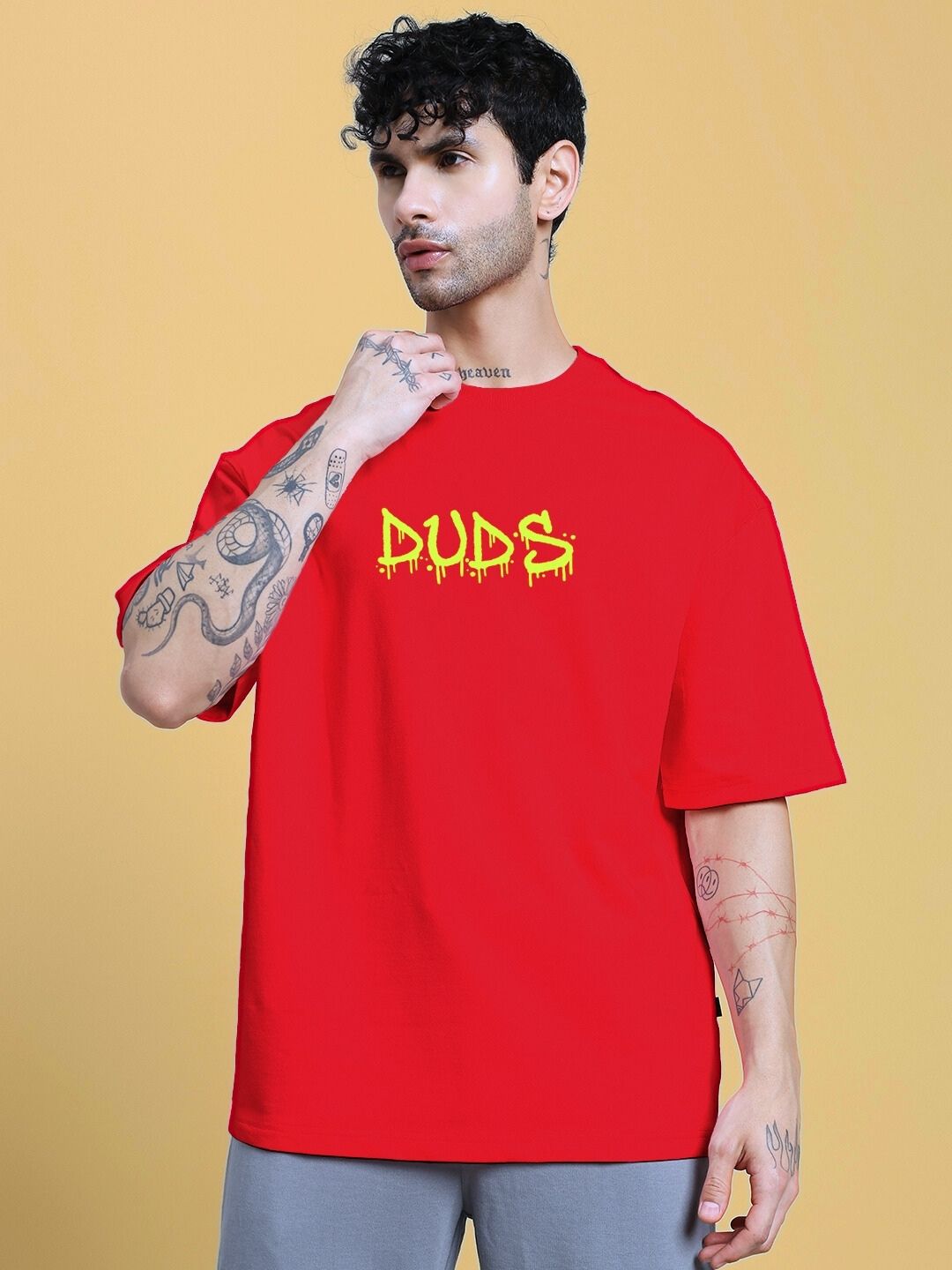 Model wearing NO WAR OVER-SIZED T-SHIRT IN RED with graphic design, standing against a yellow background.