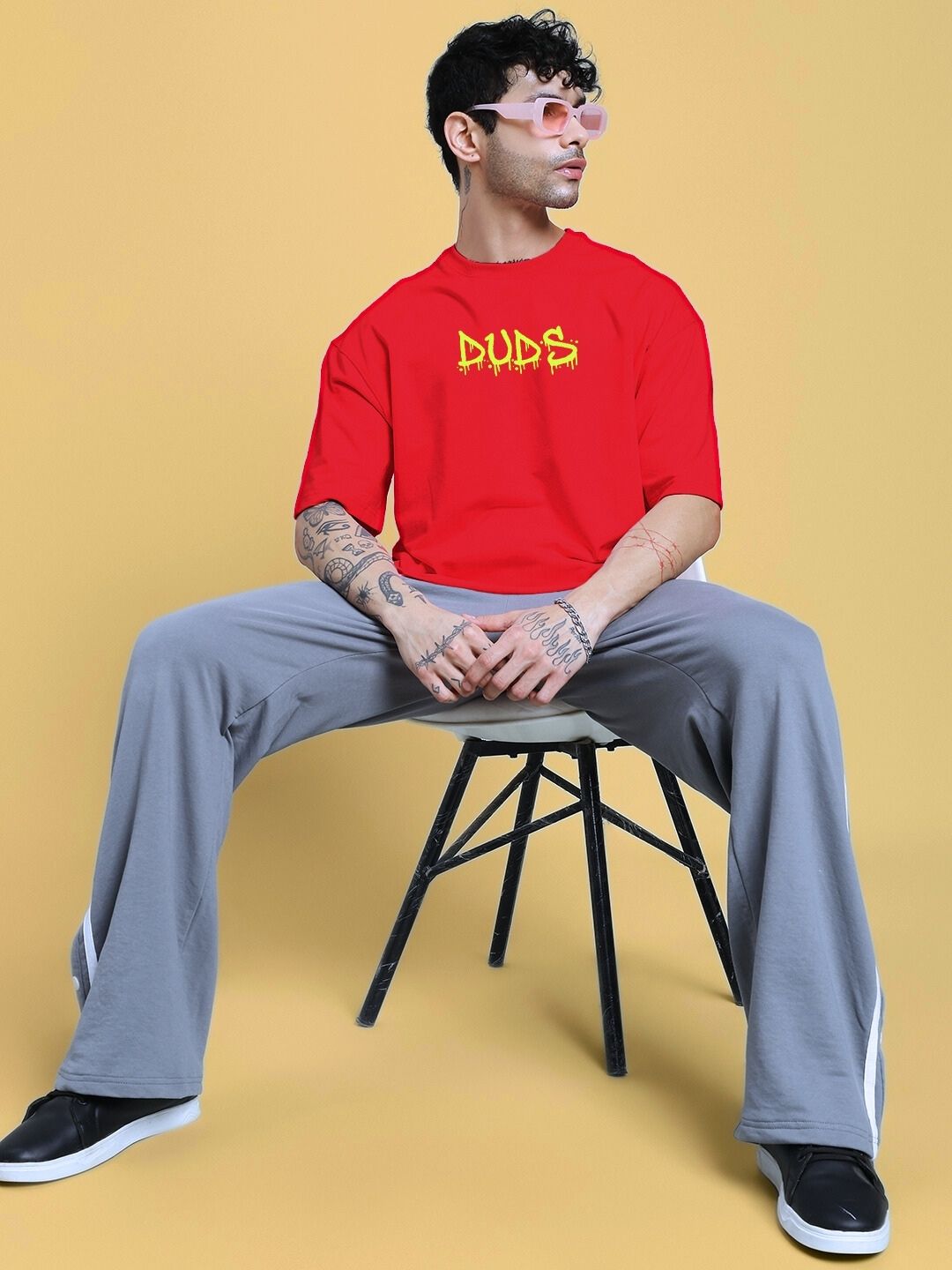 NO WAR OVER-SIZED T-SHIRT IN RED worn by model in casual style, featuring a bold graffiti design, seated against a neutral background.