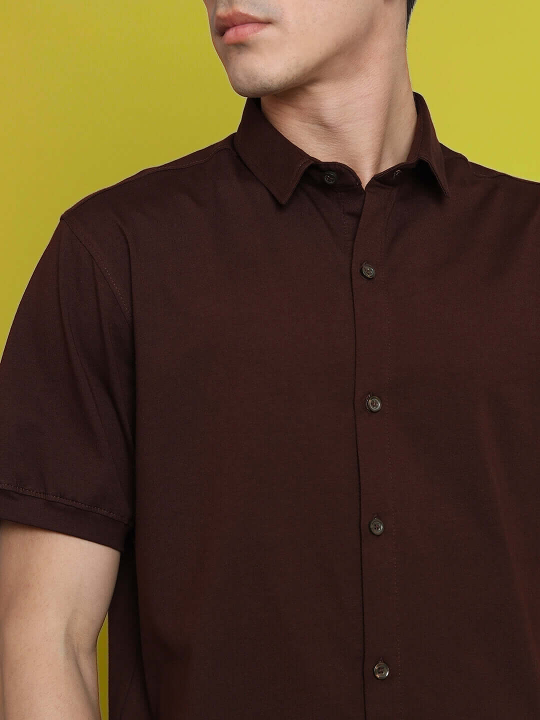 NOIR coffee brown shirt with half sleeves, worn by a model, showcasing a wrinkle-free design and curved hem. Made from 100% cotton Lycra.