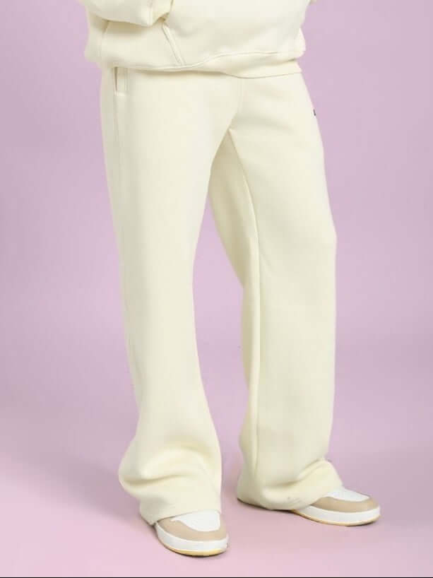 Person wearing OCEAN BUDDIES JOGGER OFF-WHITE in a casual pose against a pink background, showcasing comfort and style.