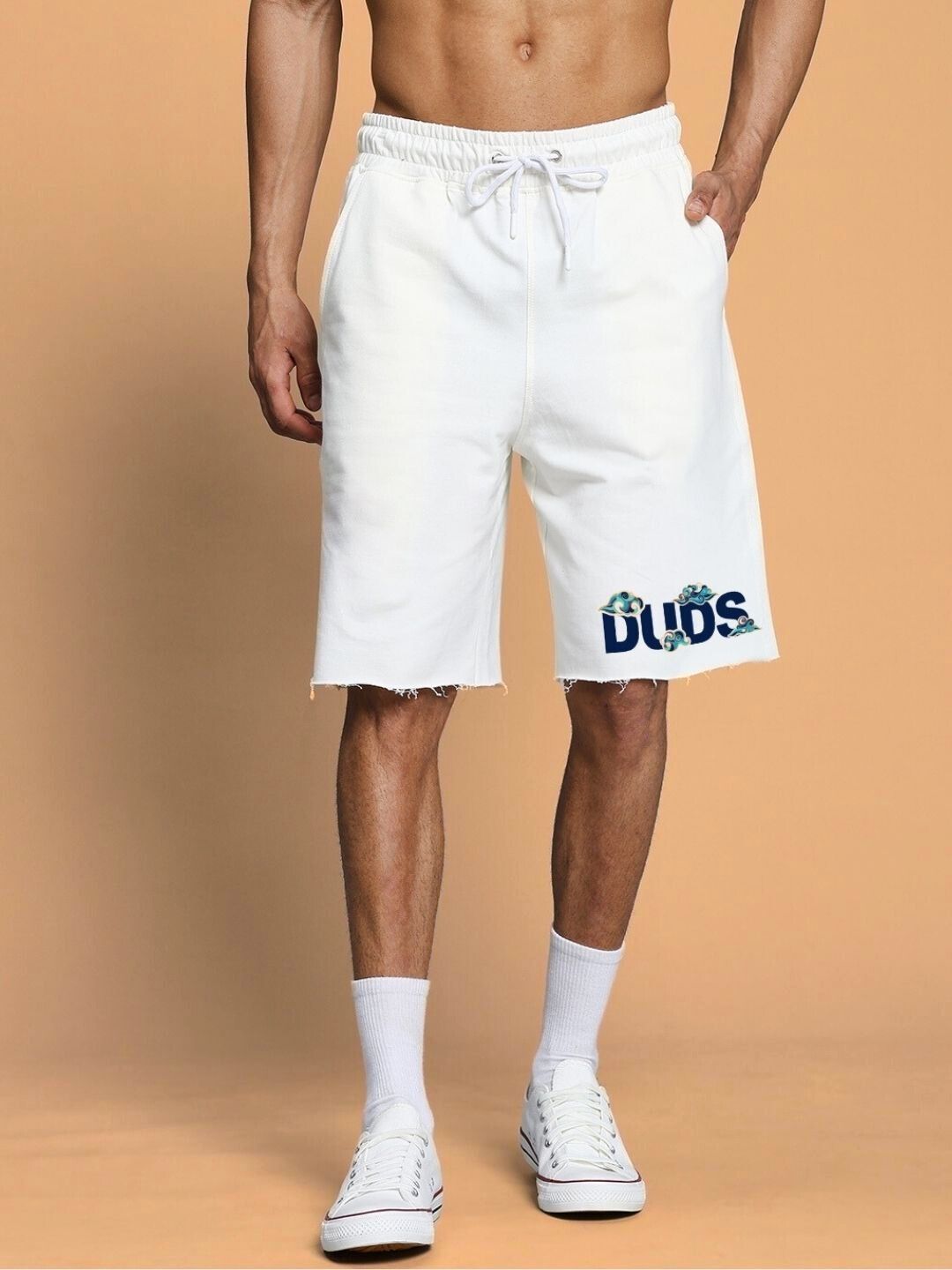 Off-white men's shorts with drawstring waist and 'Dudes' graphic print, paired with white sneakers.