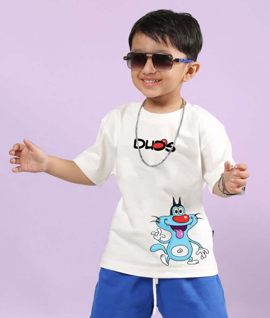 Boy wearing OGGY PRINTED T-SHIRT FOR BOYS AND GIRLS OFF WHITE, smiling with sunglasses and blue shorts, playful design.