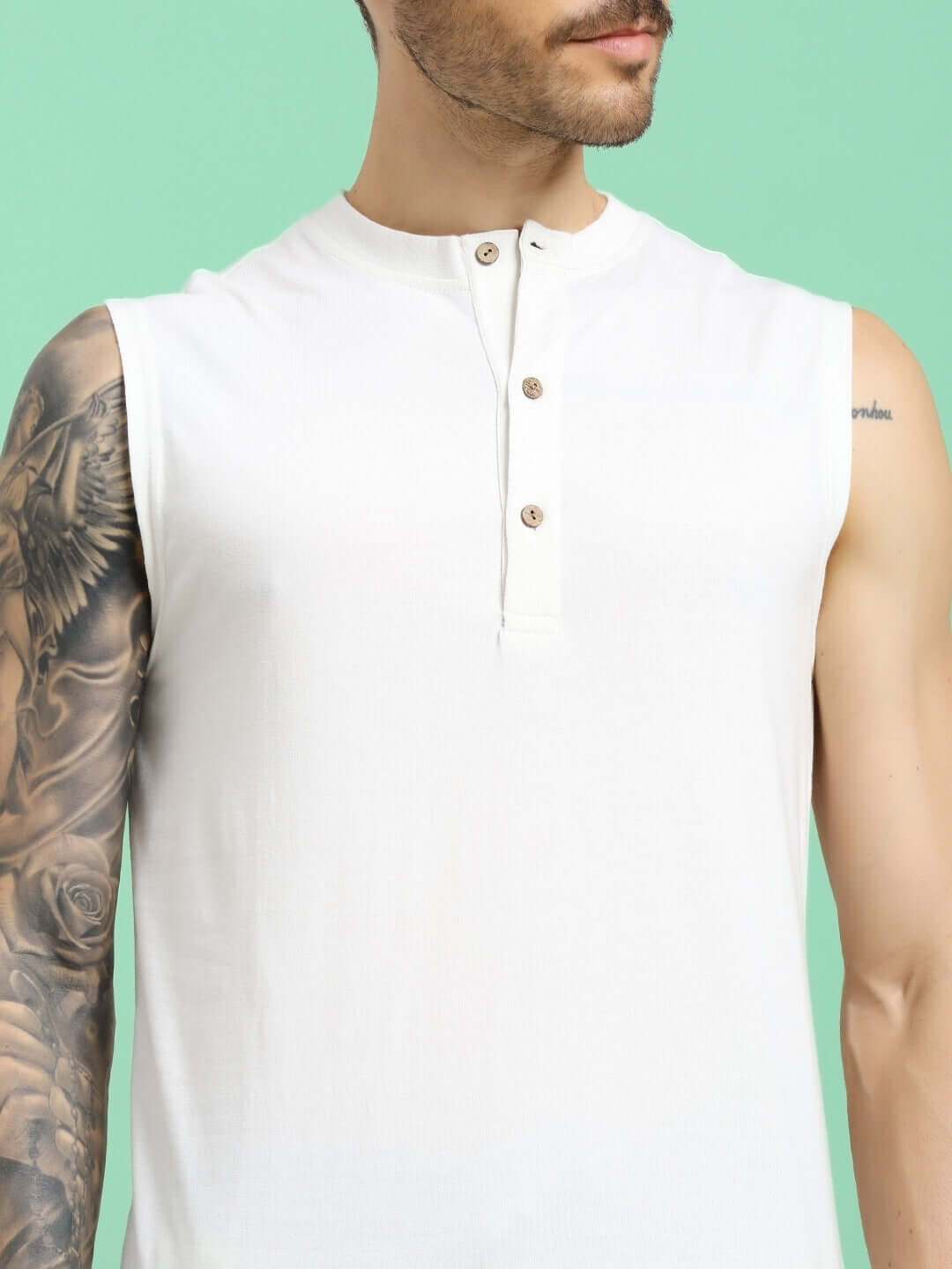 Model wearing OLIN REGULAR FIT T-SHIRT OFF-WHITE with tattooed arm on green background, showcasing front button detail.
