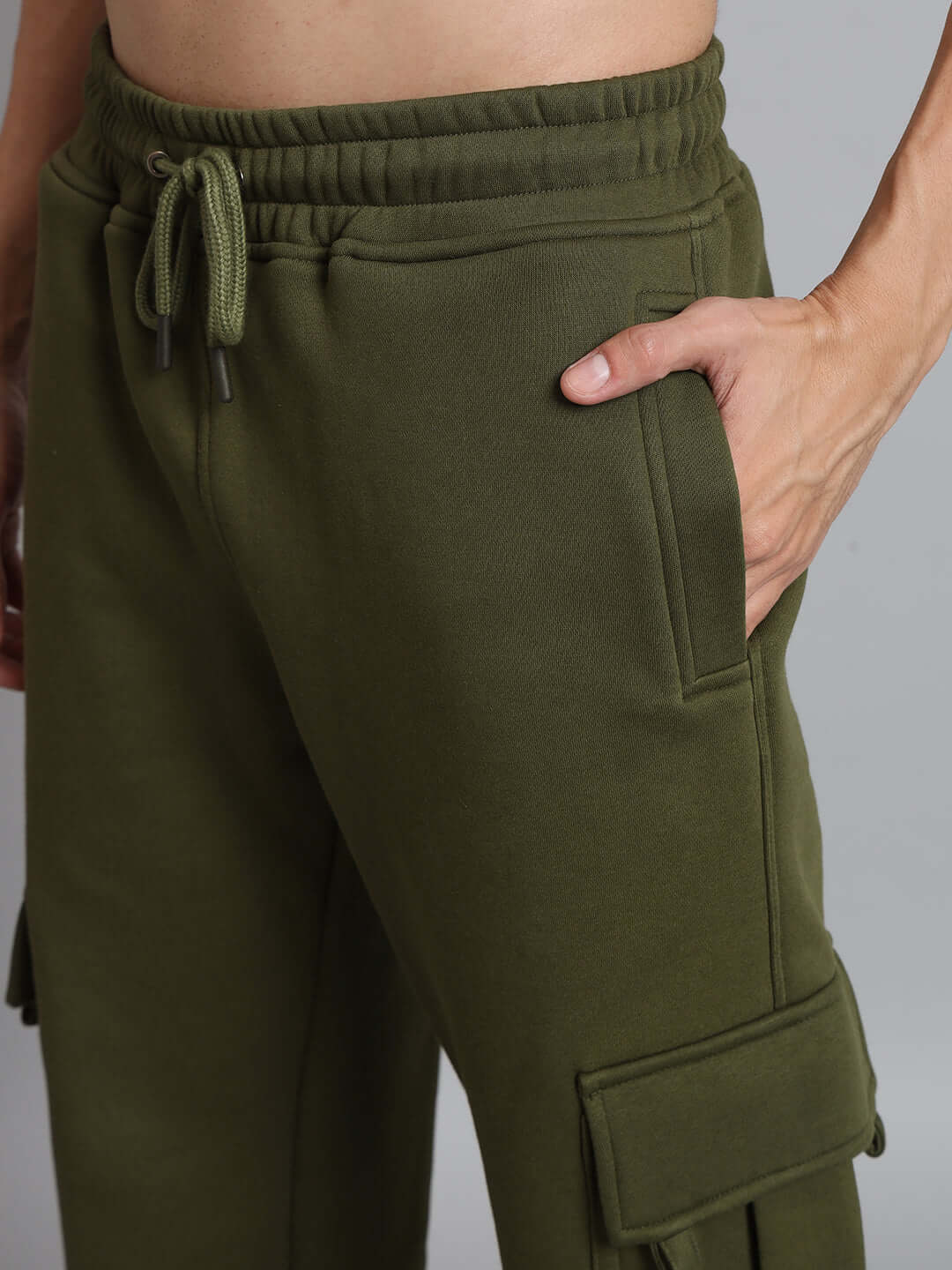 Close-up of a person wearing olive green relaxed fit fleece cargo pants with side pockets, showcasing a casual style.