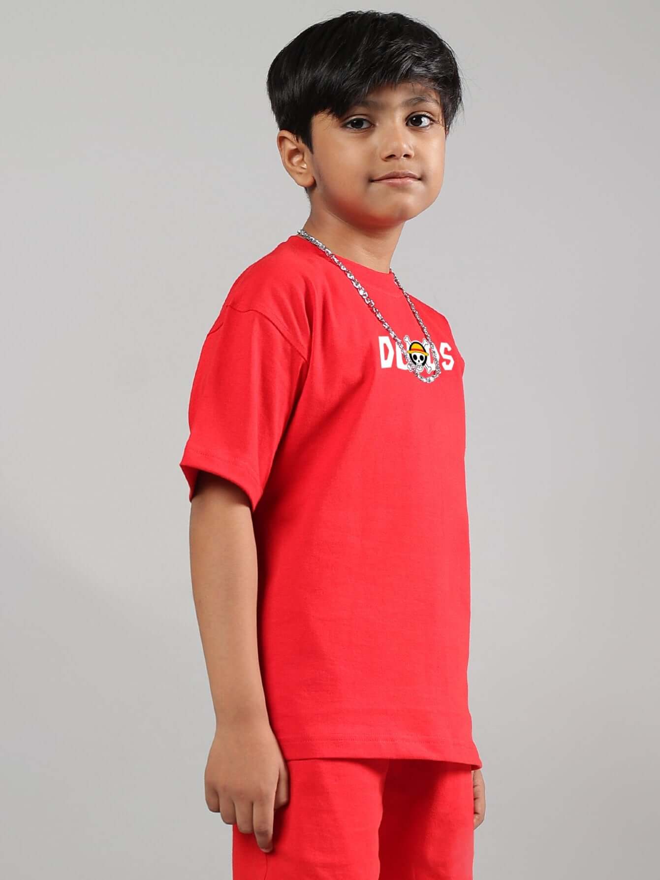 Child wearing red One Piece t-shirt by DUDS, showcasing side view of casual fit for boys and girls.
