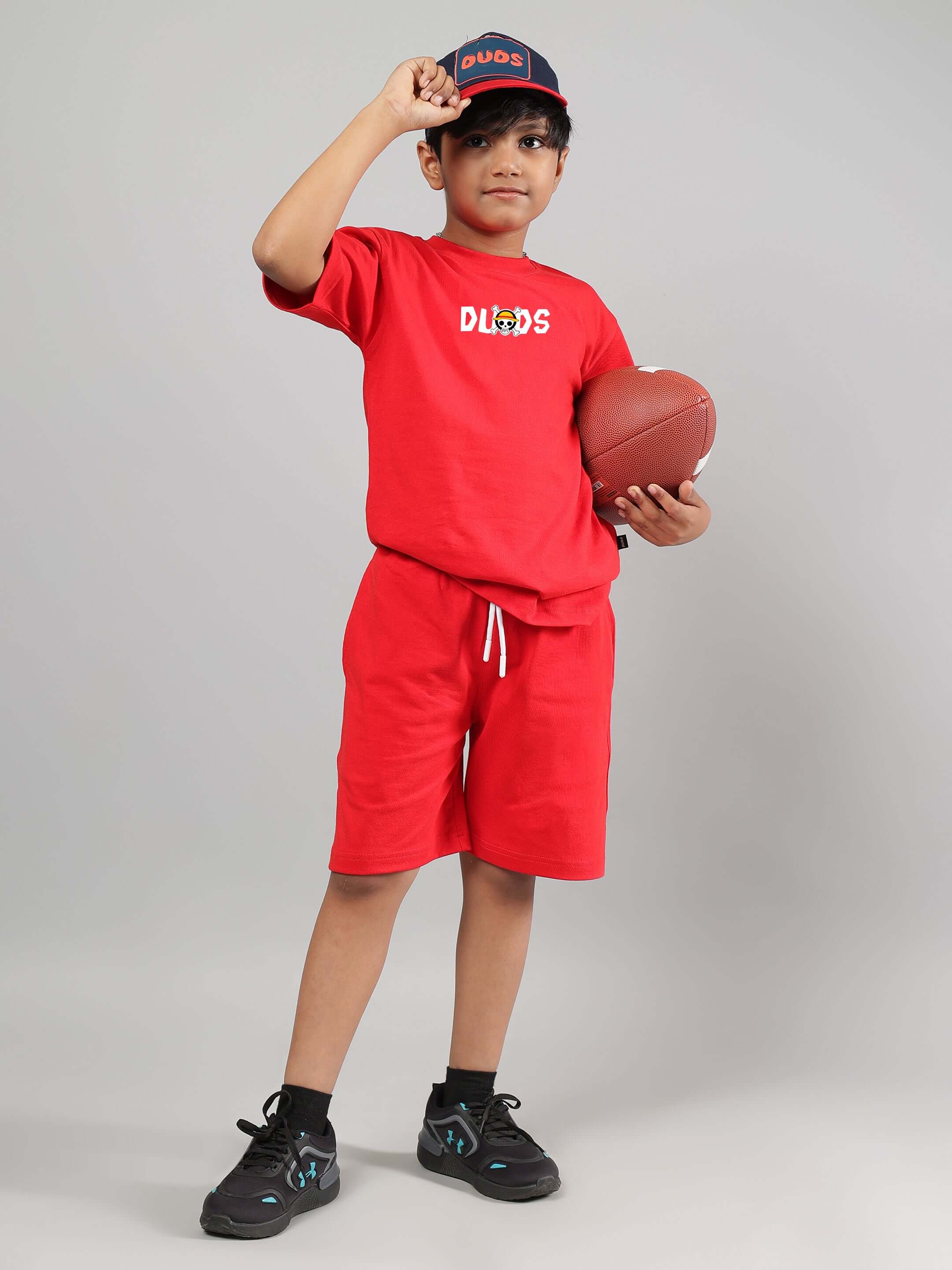 Boy wearing red ONE PIECE T-shirt with football, customizable fit available. Handmade by DUDS, ships in 7-10 days.