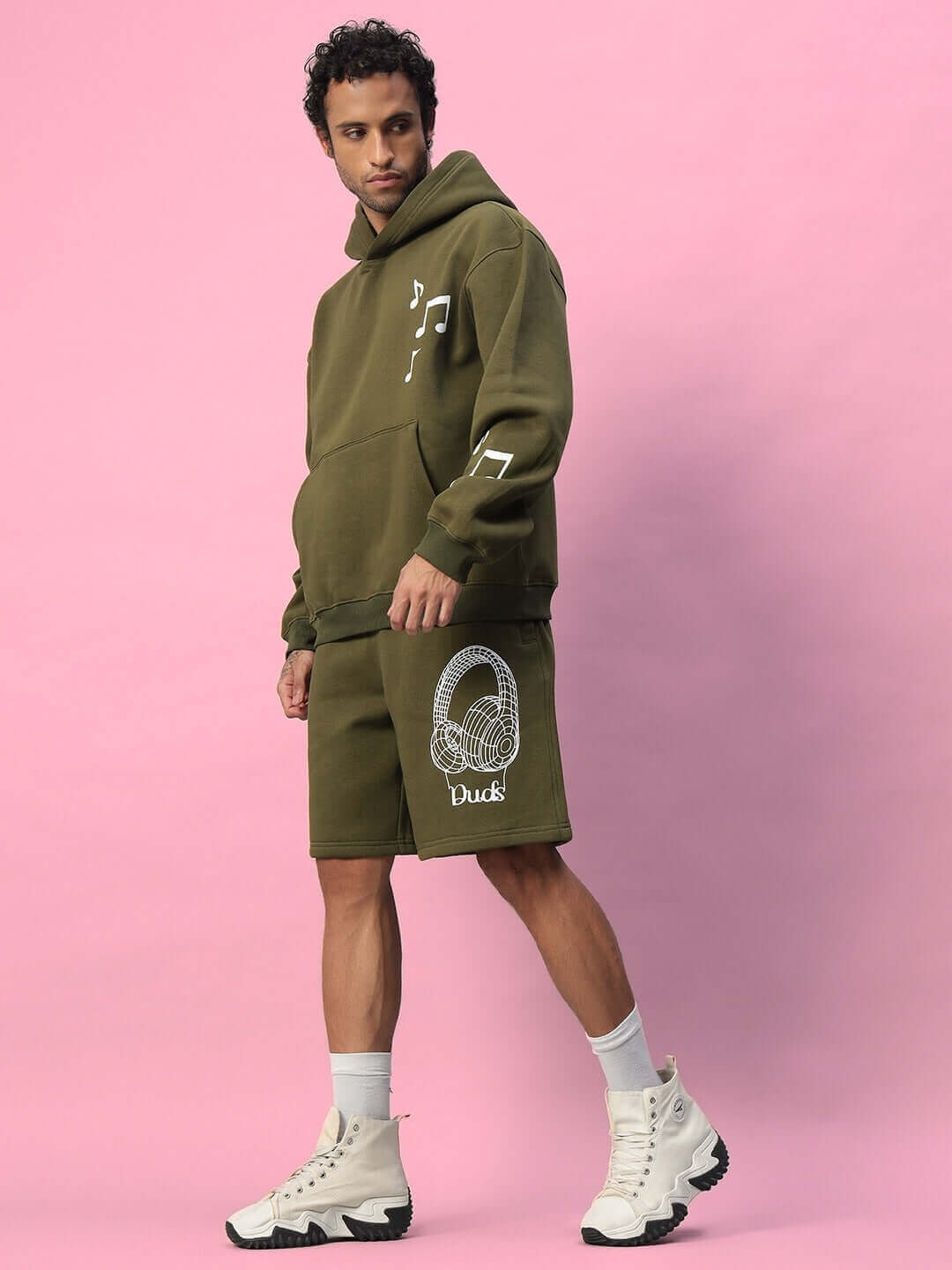 Model wearing OPERA FLEECE HOODIE OLIVE GREEN with matching shorts, showcasing stylish casual wear.