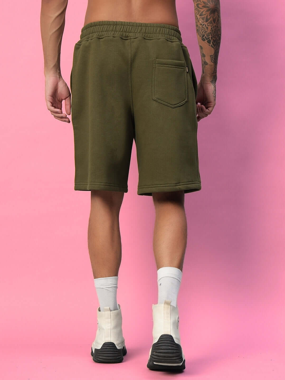 Back view of OPERA FLEECE SHORTS OLIVE GREEN worn by model on pink background.