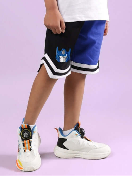 Child wearing Optimus Prime black-blue shorts for boys and girls, featuring custom fit option, paired with colorful sneakers.