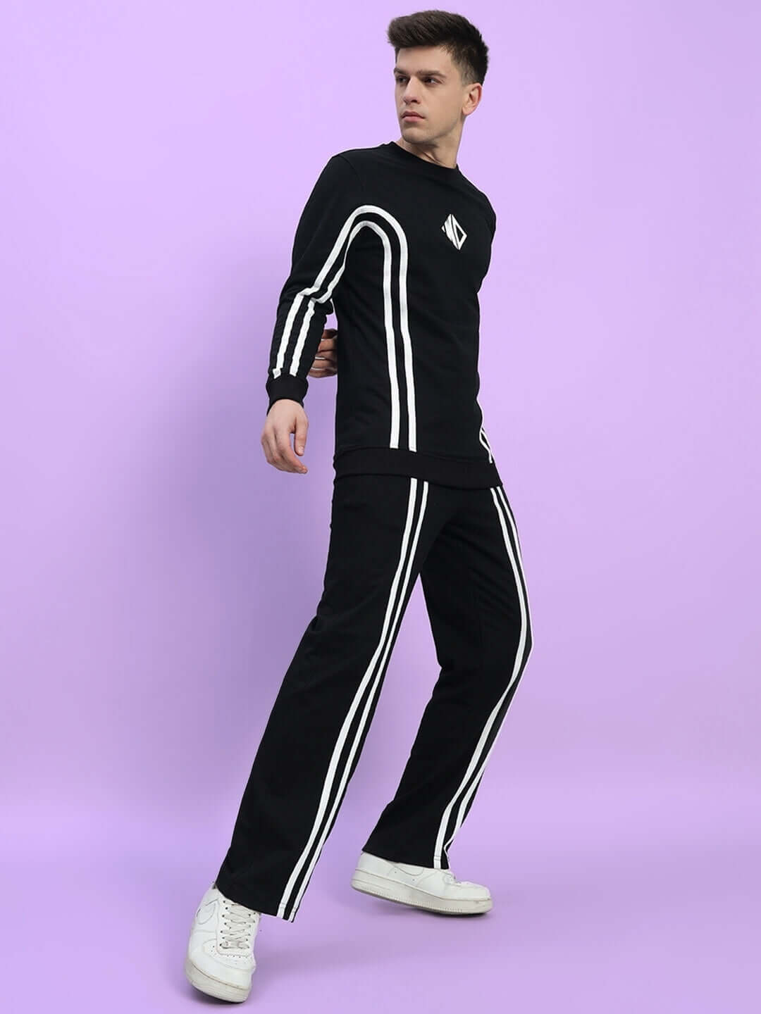 Model wearing black OUTLOOK 2 Stripe jogger with white stripes, showcasing modern tailored sportswear look by DUDS on purple backdrop.