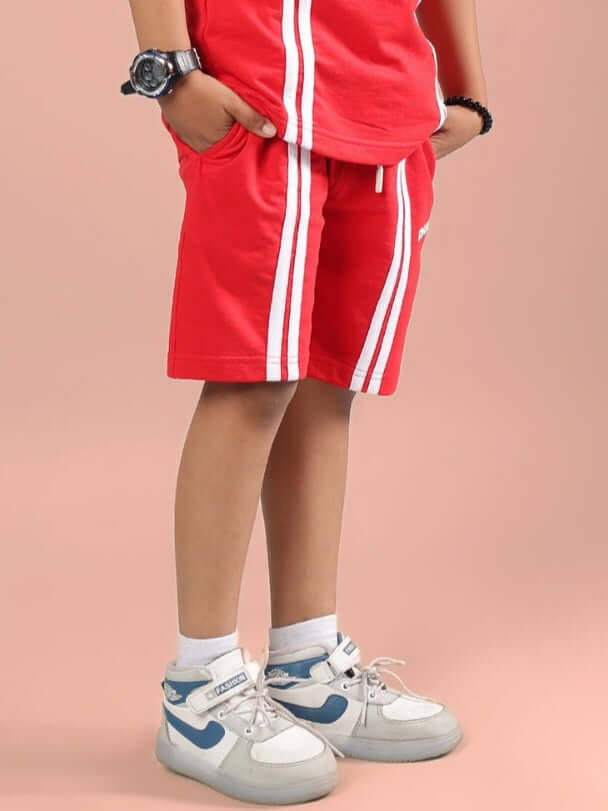 Child wearing OUTLOOK SHORTS FOR BOYS GIRLS RED with white stripes, sporty shoes, and a watch, perfect for active lifestyles.