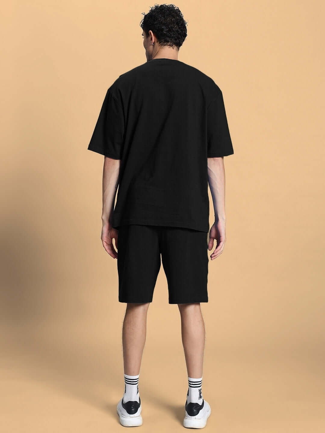 Rear view of model wearing OUTLOOK SUMMER CO-ORD SHORTS SET BLACK, highlighting oversized tee and shorts in sleek black.