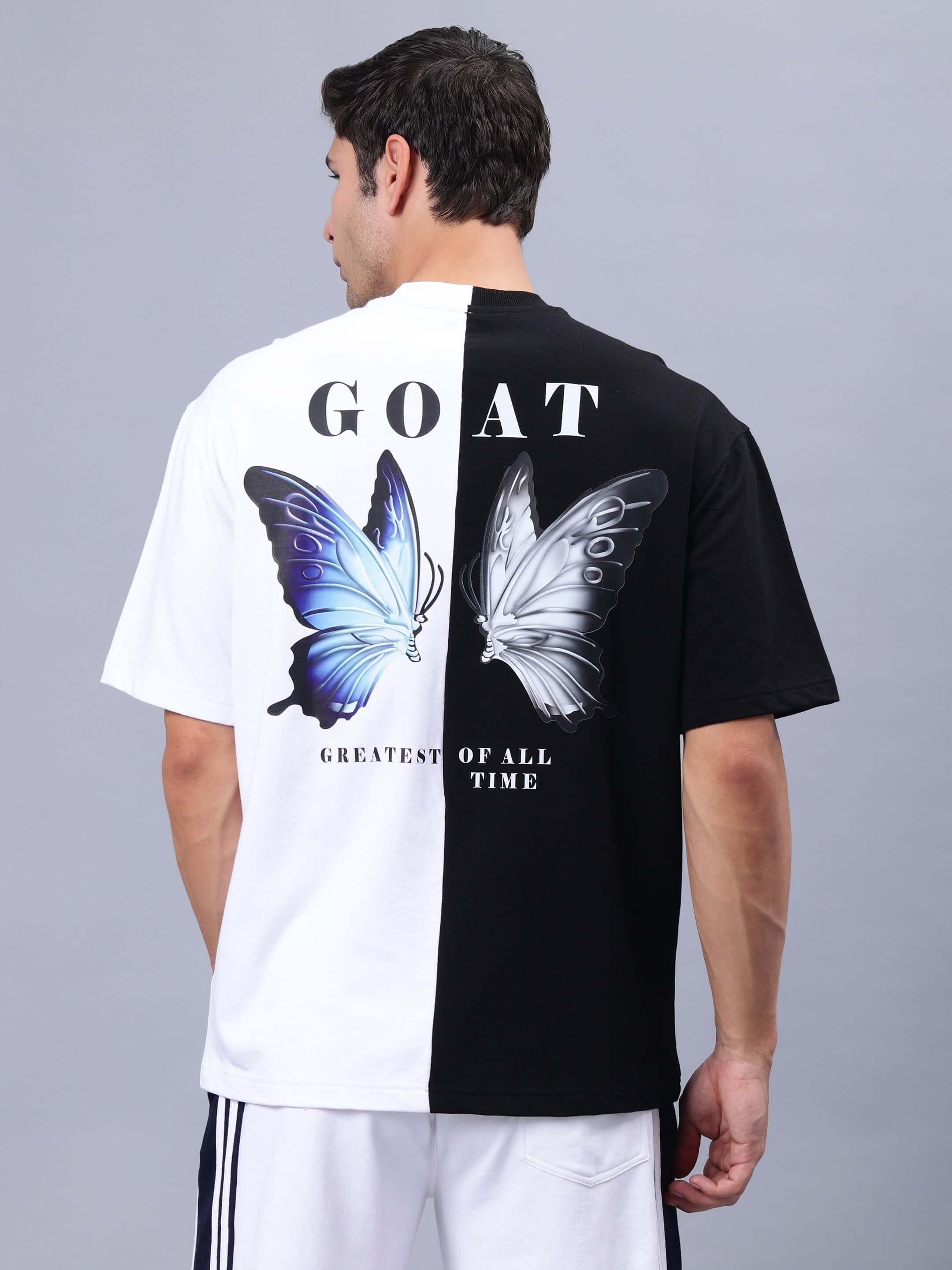 Men's G.O.A.T oversized T-shirt in black and white, featuring butterfly graphics and bold lettering on the back.