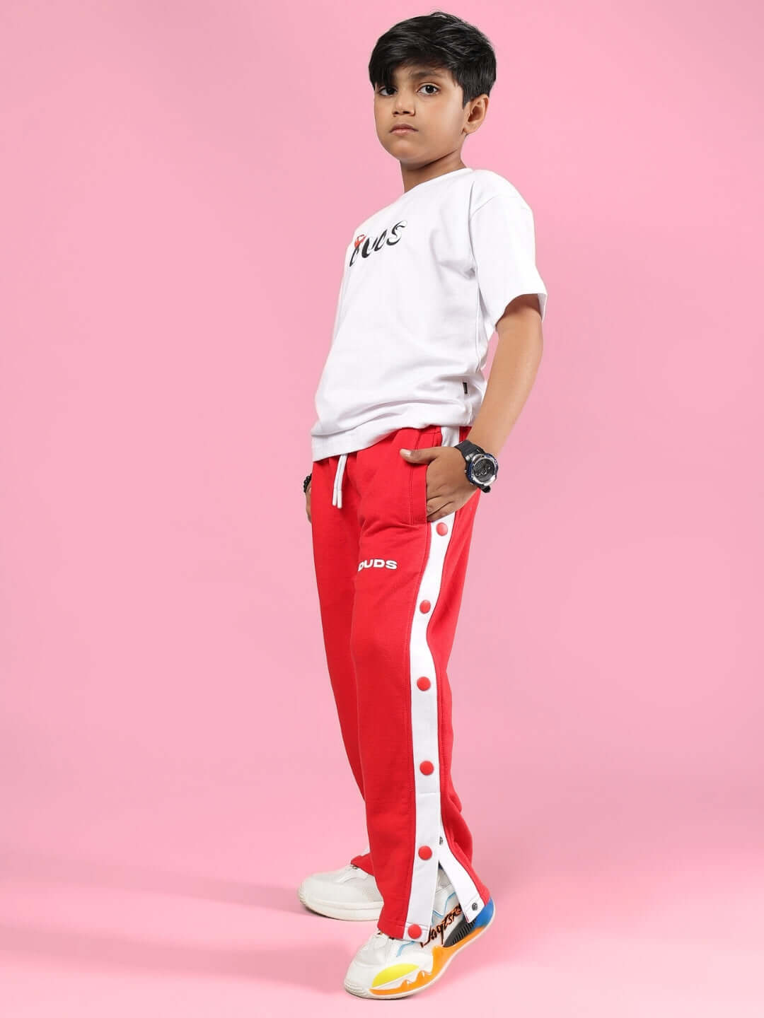 Child wearing PALOMA CO-ORD FOR BOYS & GIRLS WHITE RED with white top and red pants on a pink background