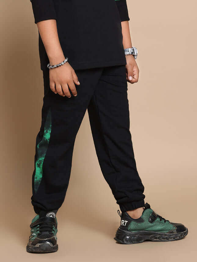 Child wearing black panda co-ord set with green accents, suitable for boys and girls, showcasing trendy footwear and casual style.