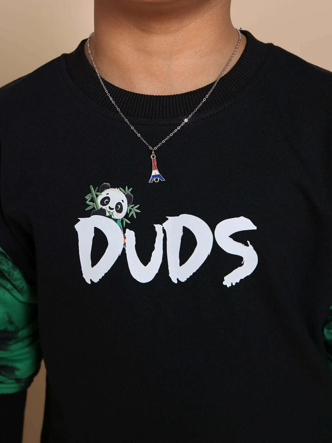 Child wearing a black panda-themed co-ord set for boys and girls by DUDS with green detailing and a necklace.