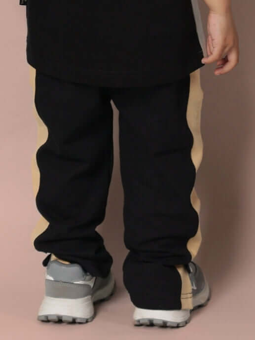 Child wearing PARADISE JOGGER FOR BOYS & GIRLS BLACK BEIGE with sporty design, back view.