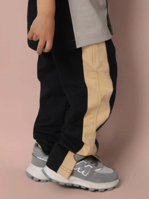 Child wearing PARADISE JOGGER FOR BOYS & GIRLS BLACK BEIGE with sneakers, showcasing stylish and comfortable joggers.