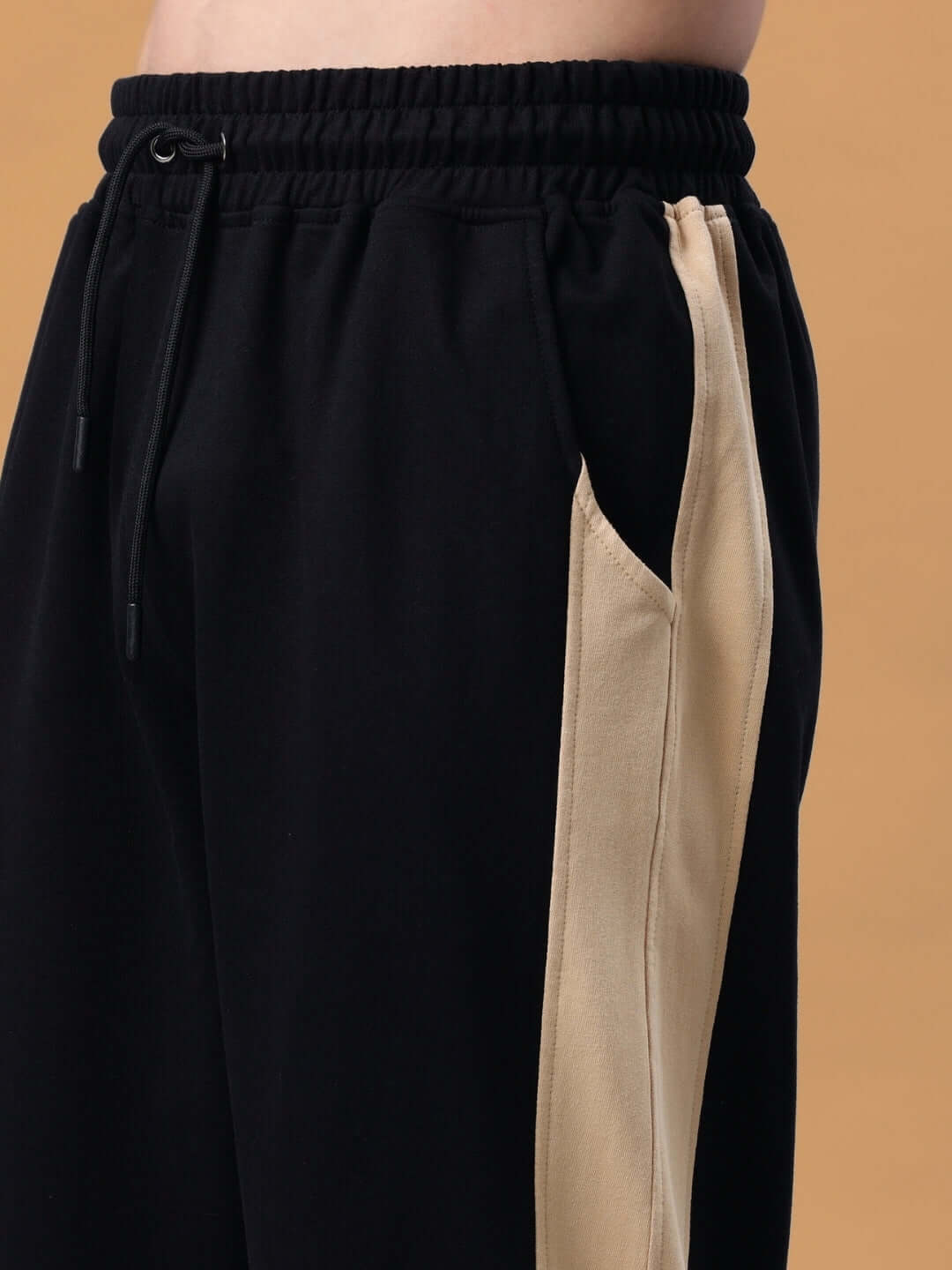 Close-up of Paradise Side Slit Joggers in black-beige with custom fit option, showcasing side slit and waistband detail.