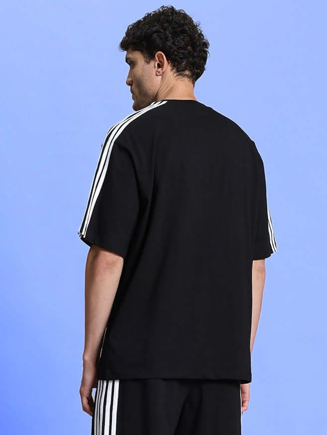 Man wearing PARKA OVER-SIZED CLASSIC T-SHIRT BLACK with relaxed fit and premium cotton fabric, showcasing back view.