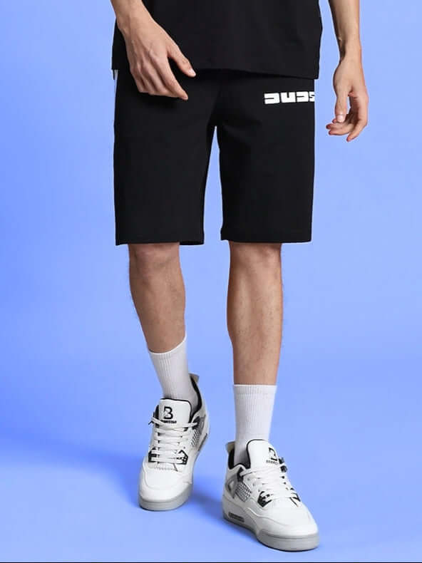 PARKA REGULAR FIT SHORTS BLACK, comfortable and stylish shorts for everyday wear, shown with white sneakers and socks against a blue background.