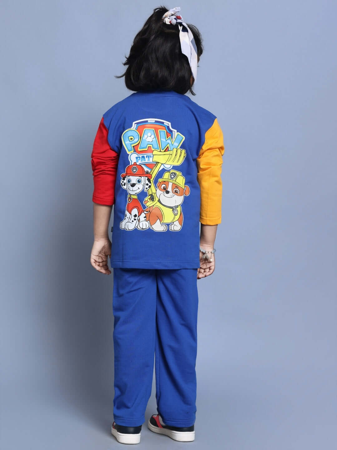 Child wearing Paw Patrol oversized co-ord set in blue-multi with colorful sleeves and cartoon characters on back, showcasing relaxed fit.