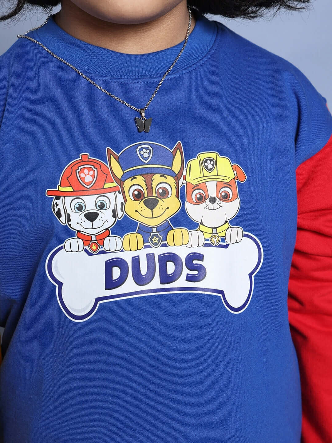 Child wearing a blue and red PAW Patrol sweatshirt featuring cartoon characters, part of an oversized co-ord set for boys and girls.