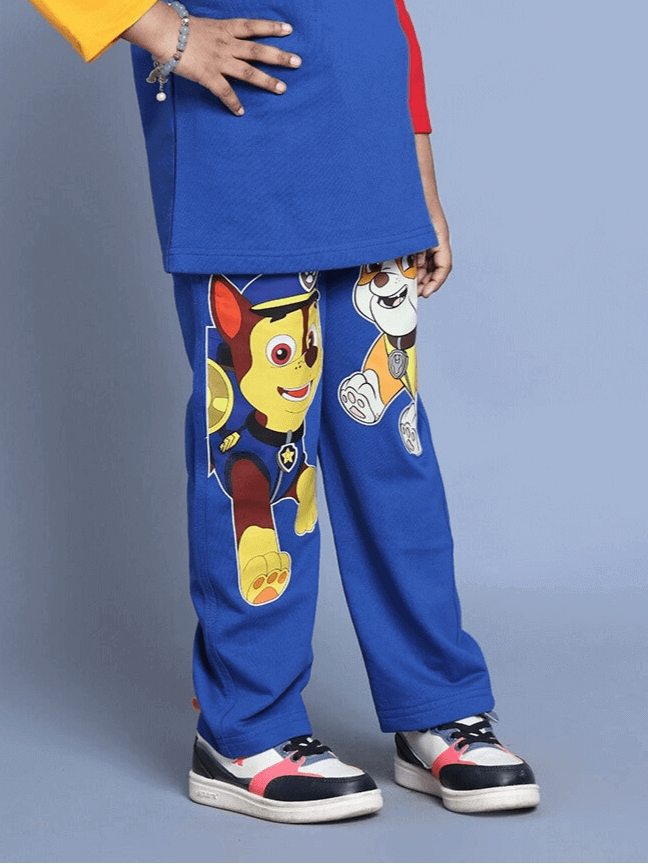 Child wearing blue Paw Patrol co-ord set with cartoon characters, elastic waistband, red and white panel joggers, and sneakers.