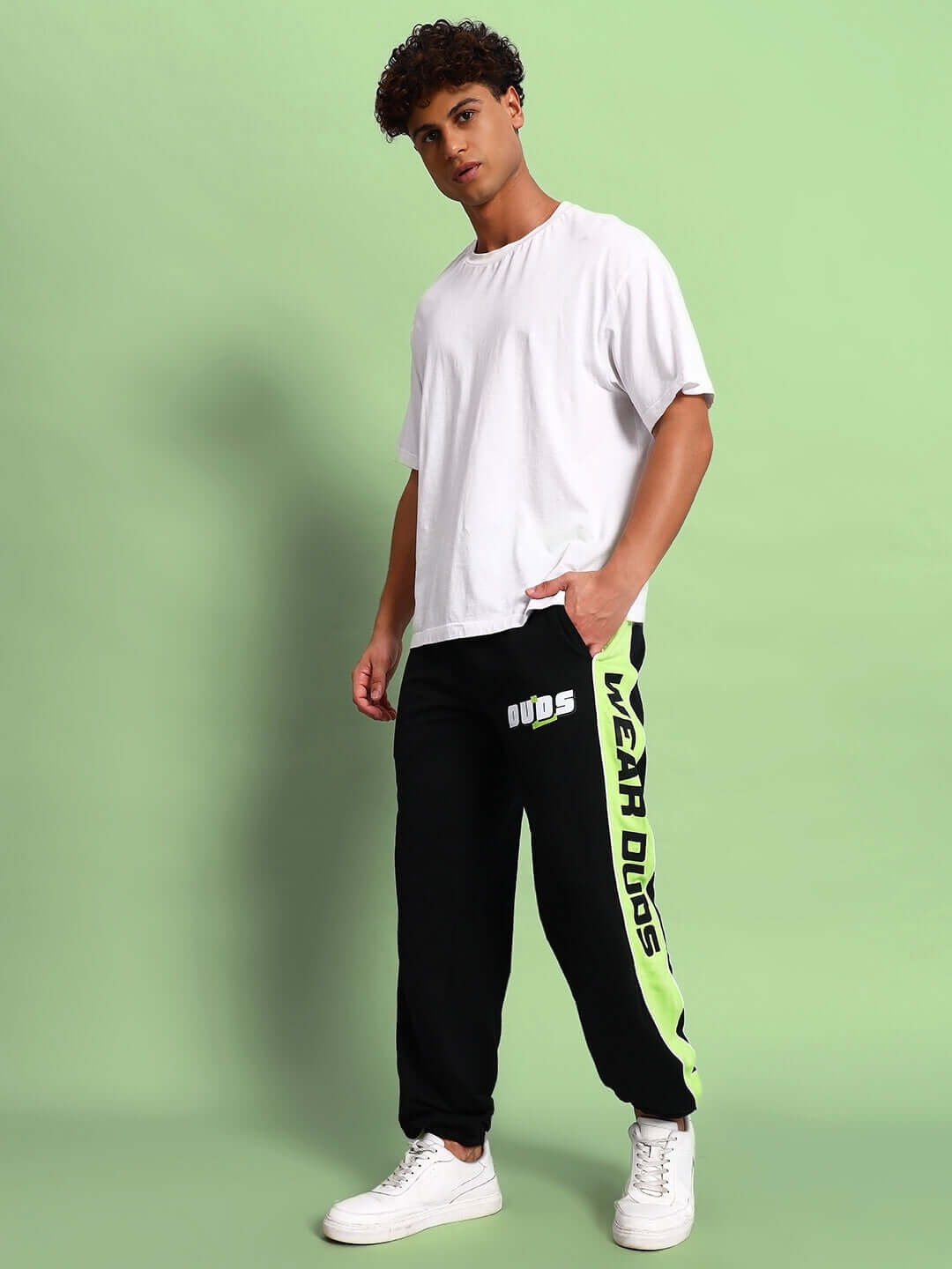 Man wearing PEPPY JOGGERS in black and neon green with "WEAR DUDS" text, standing against a light green background.