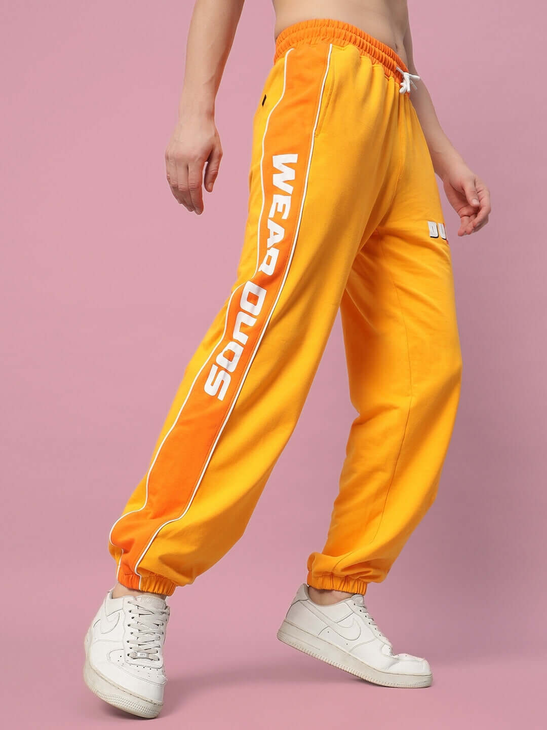 Person wearing yellow-orange Peppy Joggers with 'Wear Duds' text, showcasing trendy casual style.