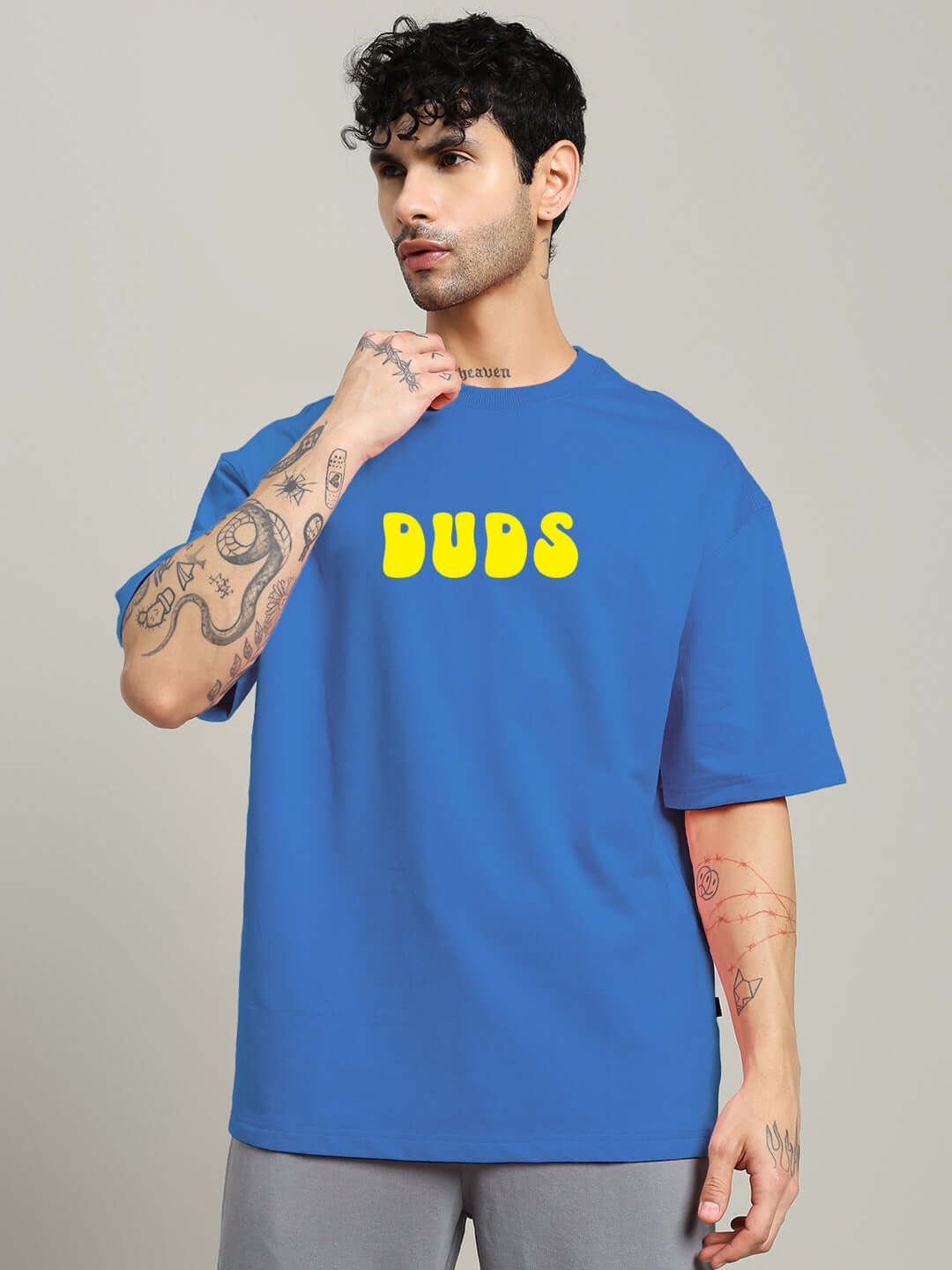 Man wearing PERSONAL TRUTH OVERSIZED T-SHIRT BLUE with yellow 'DUDS' logo on front.