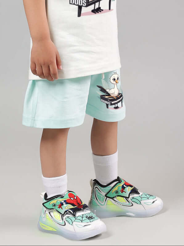 Child wearing Piano Bird Shorts for Boys Girls Sky Blue with colorful sneakers, showcasing summer fashion.