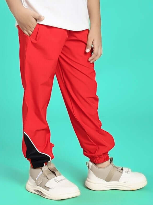 Child wearing PLEXUS JOGGER FOR BOYS AND GIRLS RED, vibrant and stylish kids' joggers on turquoise background, perfect for active play.