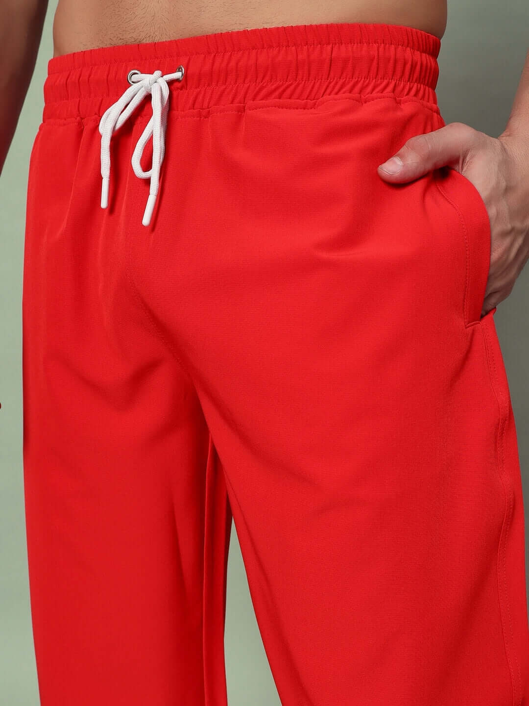 Red PLEXUS joggers with elastic waistband and drawstring, designed for custom fit and made by DUDS' experienced tailors.