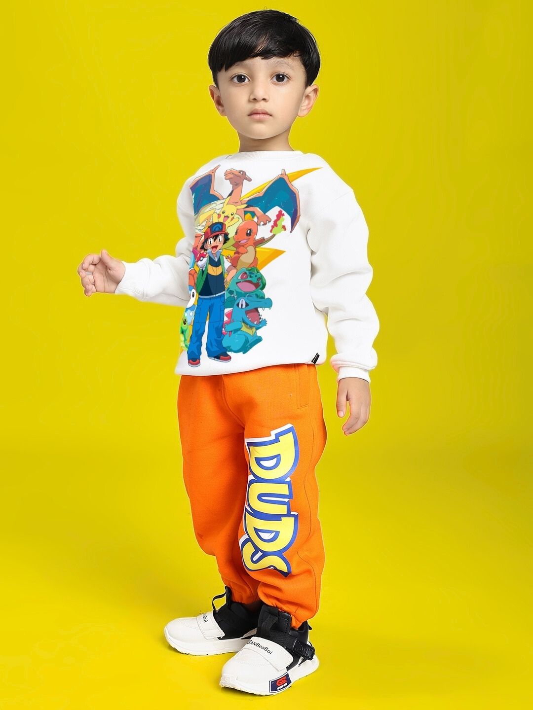 Child wearing POKEMON CO-ORD FOR BOYS AND GIRLS OFF-WHITE ORANGE with character illustrations on the top.