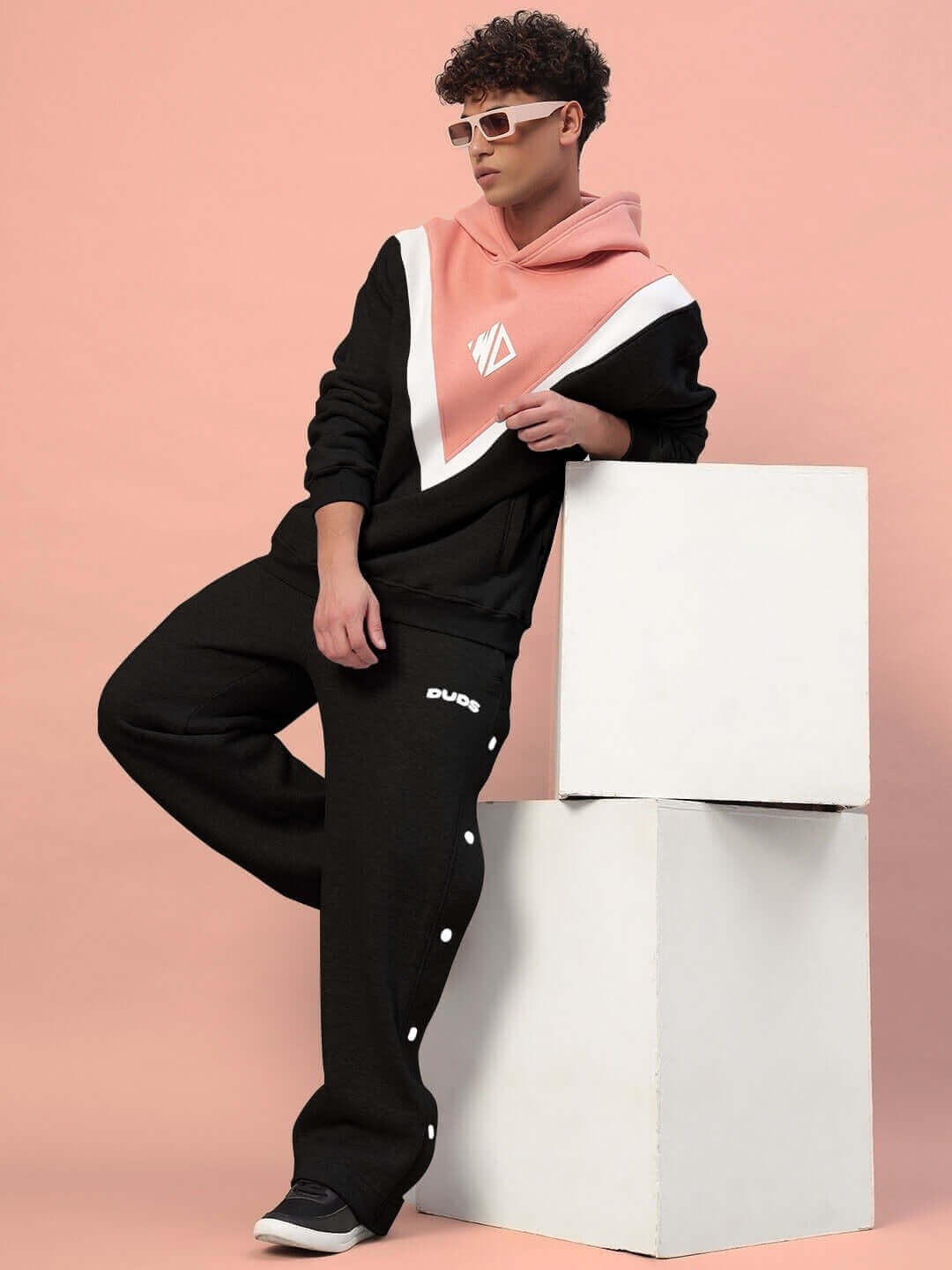 Man wearing POLAR COLORBLOCK CO-ORD BLACK PEACH streetwear set in fleece fabric, styled with peach hoodie and black pants.