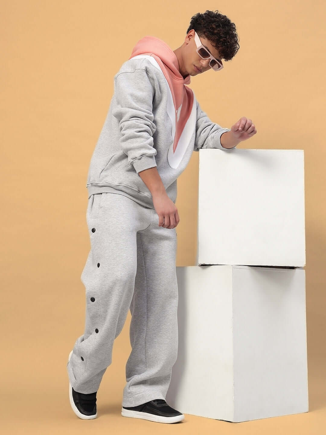 Model wearing POLAR FLEECE COLORBLOCK HOODIE GREY PEACH with peach and grey colorblocks, paired with matching pants, styled for streetwear.