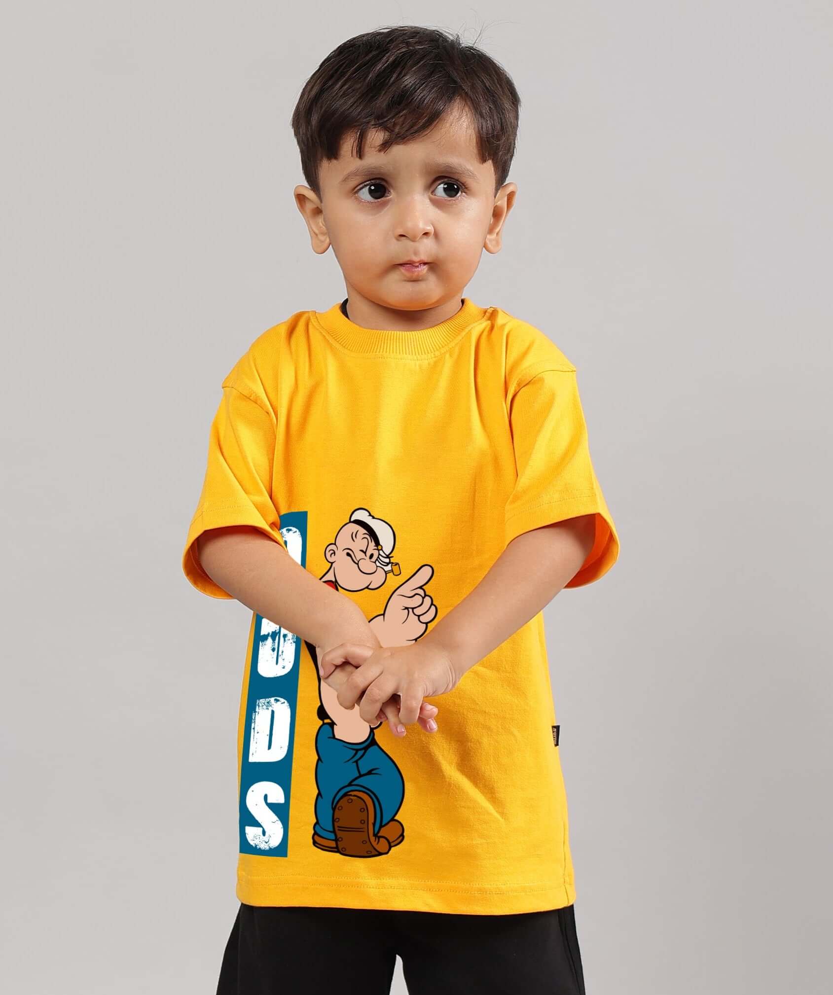 Young child wearing a yellow Popeye t-shirt with "DUDS" text, suitable for boys and girls, showcasing vibrant cartoon design.