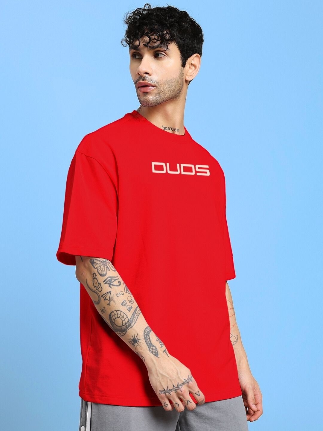 Model wearing red PORSCHE PRINTED OVER-SIZED T-SHIRT RED with relaxed fit and luxury design on a blue background