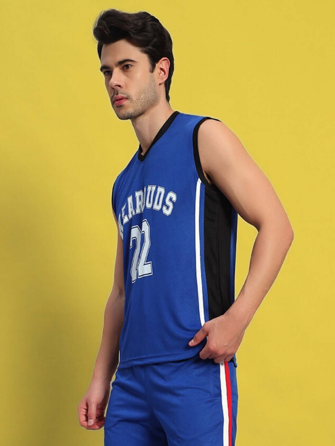 Man wearing a sleeveless blue and black sports jersey with 'BEARUDS 22' printed, standing against a yellow background.
