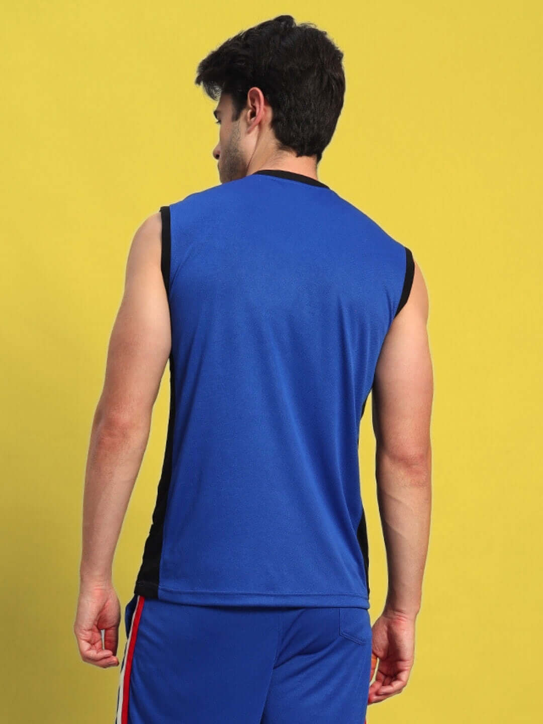 Man wearing PORTIA Gym T-Shirt in royal blue, back view against yellow background, sleeveless athletic wear for workouts.